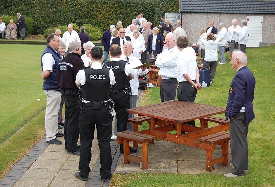 Photo of police officers talking to bowlers beside a bowling green.