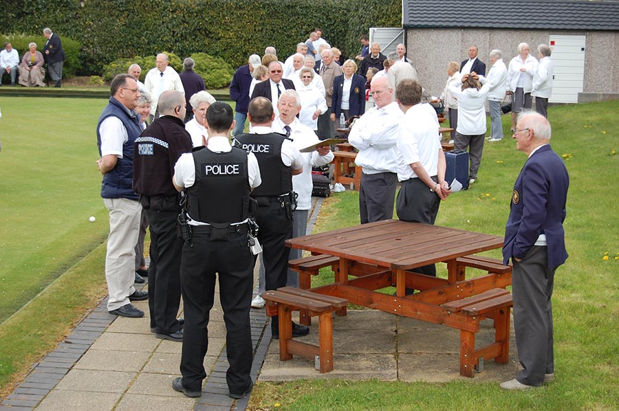 Photo of police officers talking to bowlers beside a bowling green.