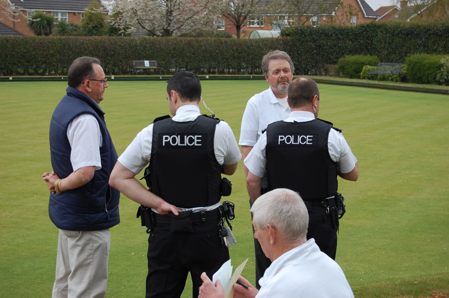 Photo of two policemen questioning a member of a bowls club.