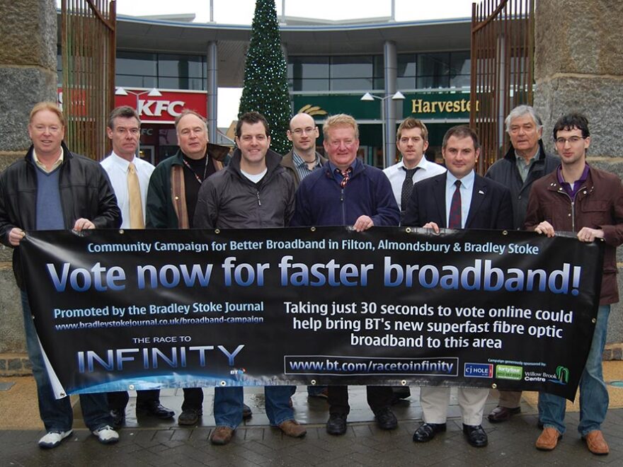 Photo of a group of people holding a banner displaying the headline, "Vote now for faster broadband".