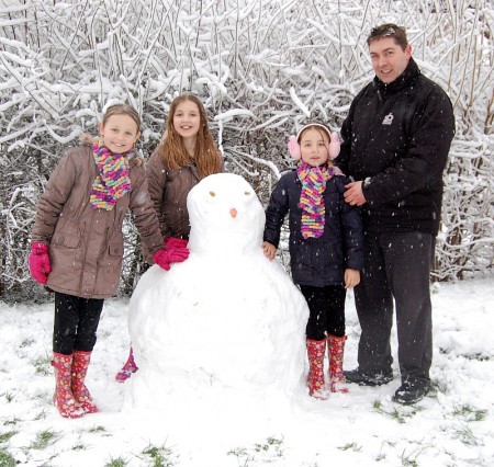 Darcy, Felicity, Penelope and dad Kevin with their snowman in Wheatfield Drive.