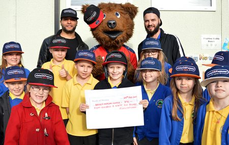 Photo of Bailey Cooper holding a cheque, accompanied by staff and pupils.