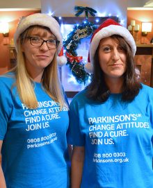 Photo of Karen Taylor (left) and Vicky Lovell in Santa hats and Parkinson's UK T-shirts.