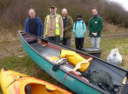Photo of volunteers standing behind canoes used to collect rubbish from the lake.