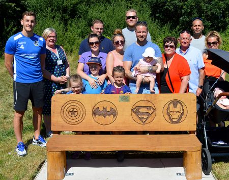 Photo of the 'celebration bench' after its unveiling, with family and friends standing behind.