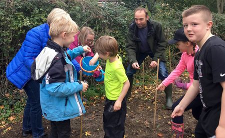 Photo of children and adults scattering wildflower seeds.