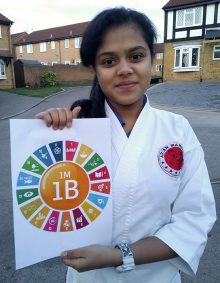 Photo of Khushi Ashwin holding a poster showing the 17 UN sustainable development goals on which the 1M1B programme is based.