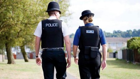 Photo (from behind) of a PCSO and a police officer walking along a path.