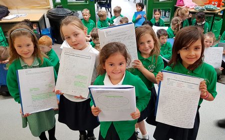 Photo of pupils proudly displaying their written work at the end of the presentation.
