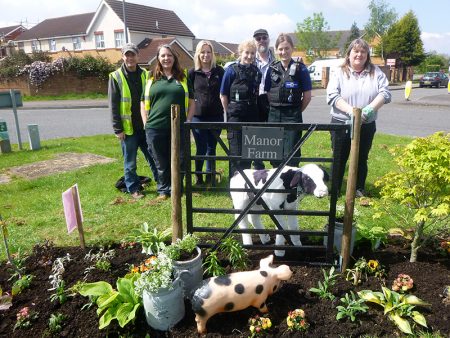 Photo of a group of people celebrating the return of 'Debbie the heifer' and 'Peppa the pig' to Manor Farm Roundabout.