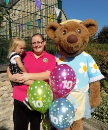 Photo of Bethan Jones holding a child and standing next to the Mama Bear's character.