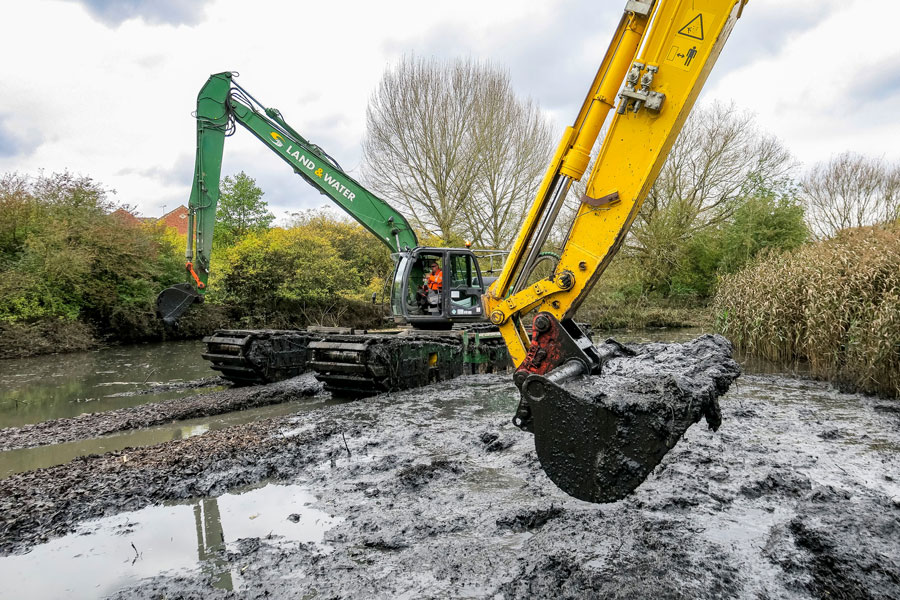 Photo of an amphibious excavator dredging a lake.