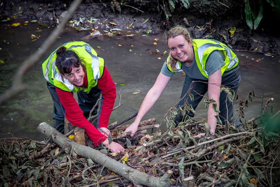 Photo of two people building a berm in a stream.