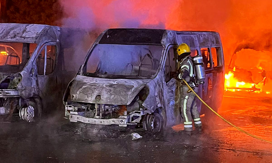 Photo of a firefighter tackling blazing minibuses.