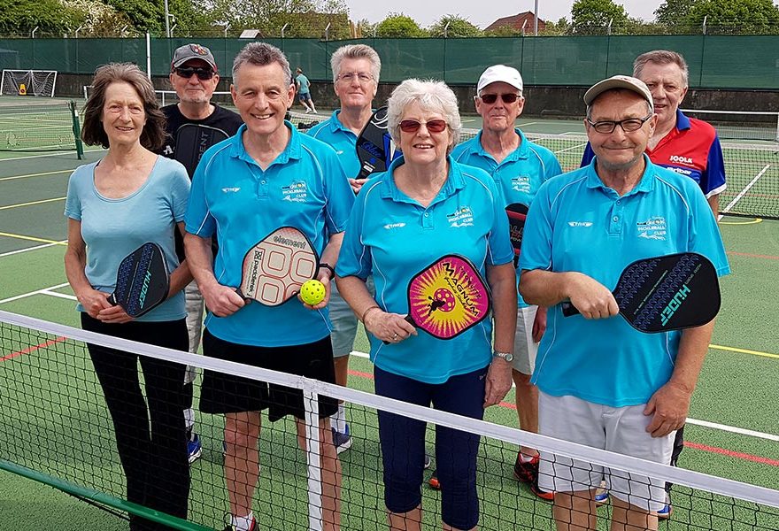 Photo of a group of pickleball players standing behind a net.
