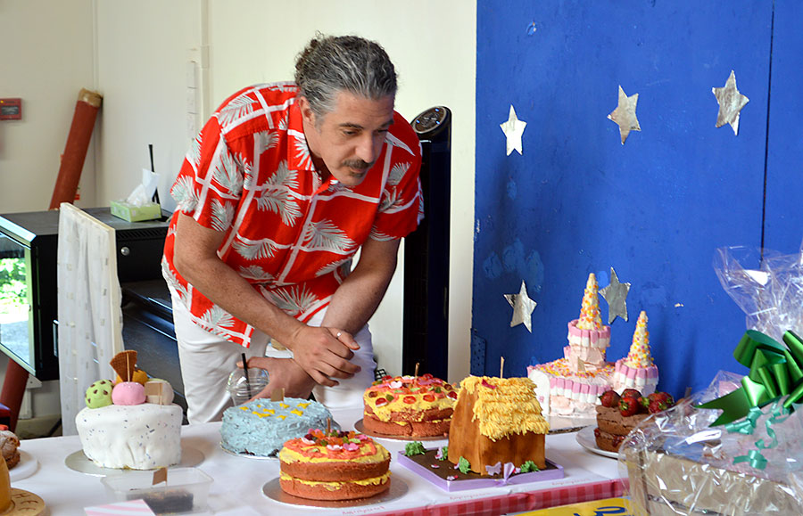 Photo of a man inspecting an array of cakes.