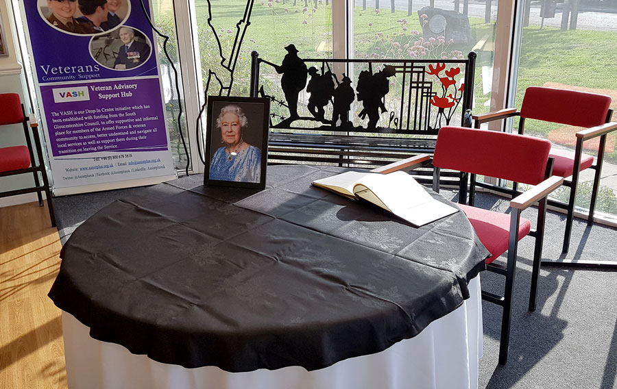 Photo of a book of condolence on a table, alongside a photo of HM Queen Elizabeth II.
