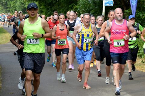 Photo of a large number of runners wearing race numbers and running along a path.