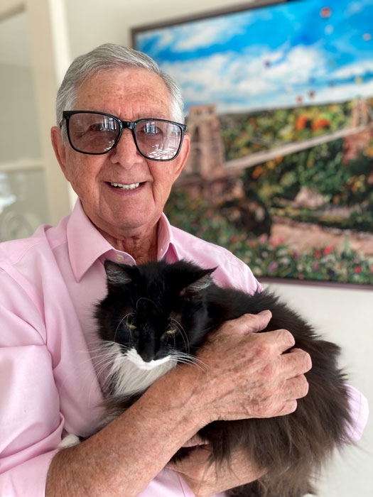 Photo of a man in a pink shirt holding a black and white cat.