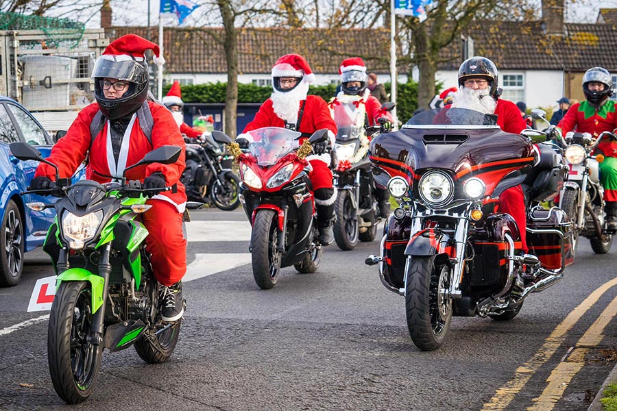 Photo of a column of motorcycles with riders dressed in Santa outfits.