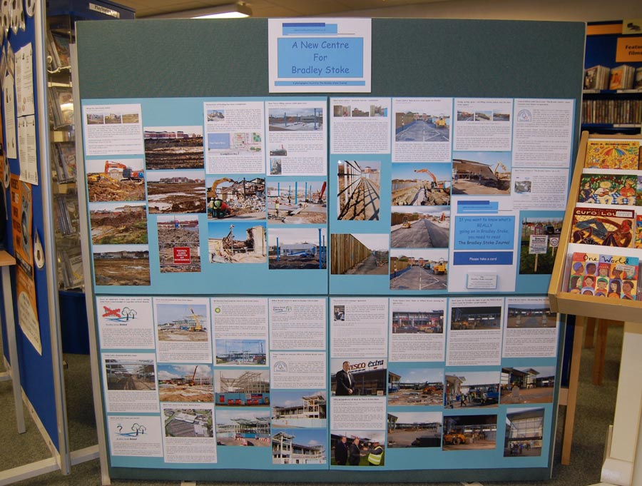 Photo of a large display board with photos and article printouts attached.